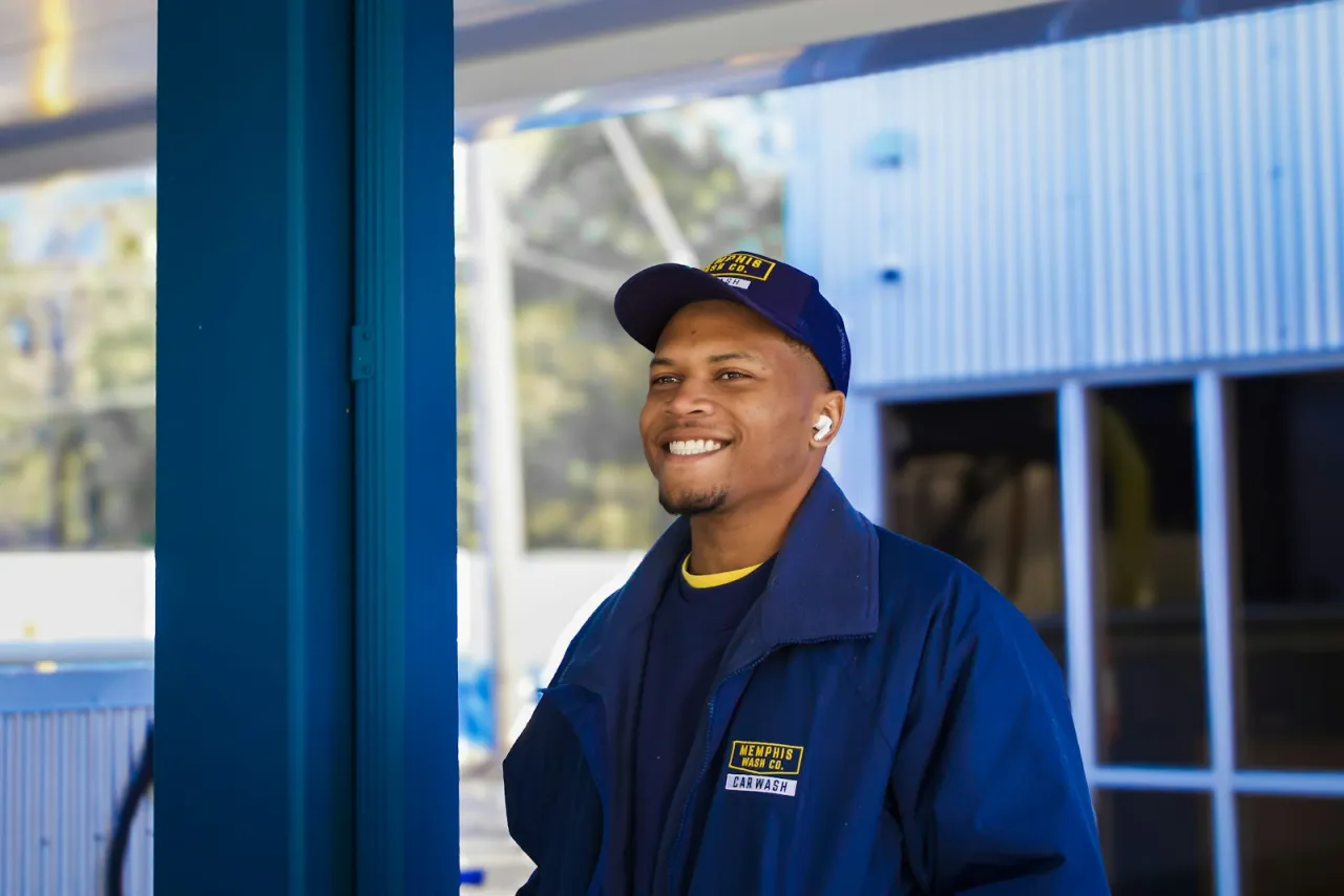 Smiling HVAC service technician in a blue work jacket at the shop